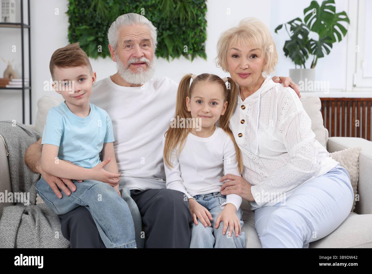 Großeltern mit ihren Enkelkindern auf dem Sofa zu Hause Stockfoto