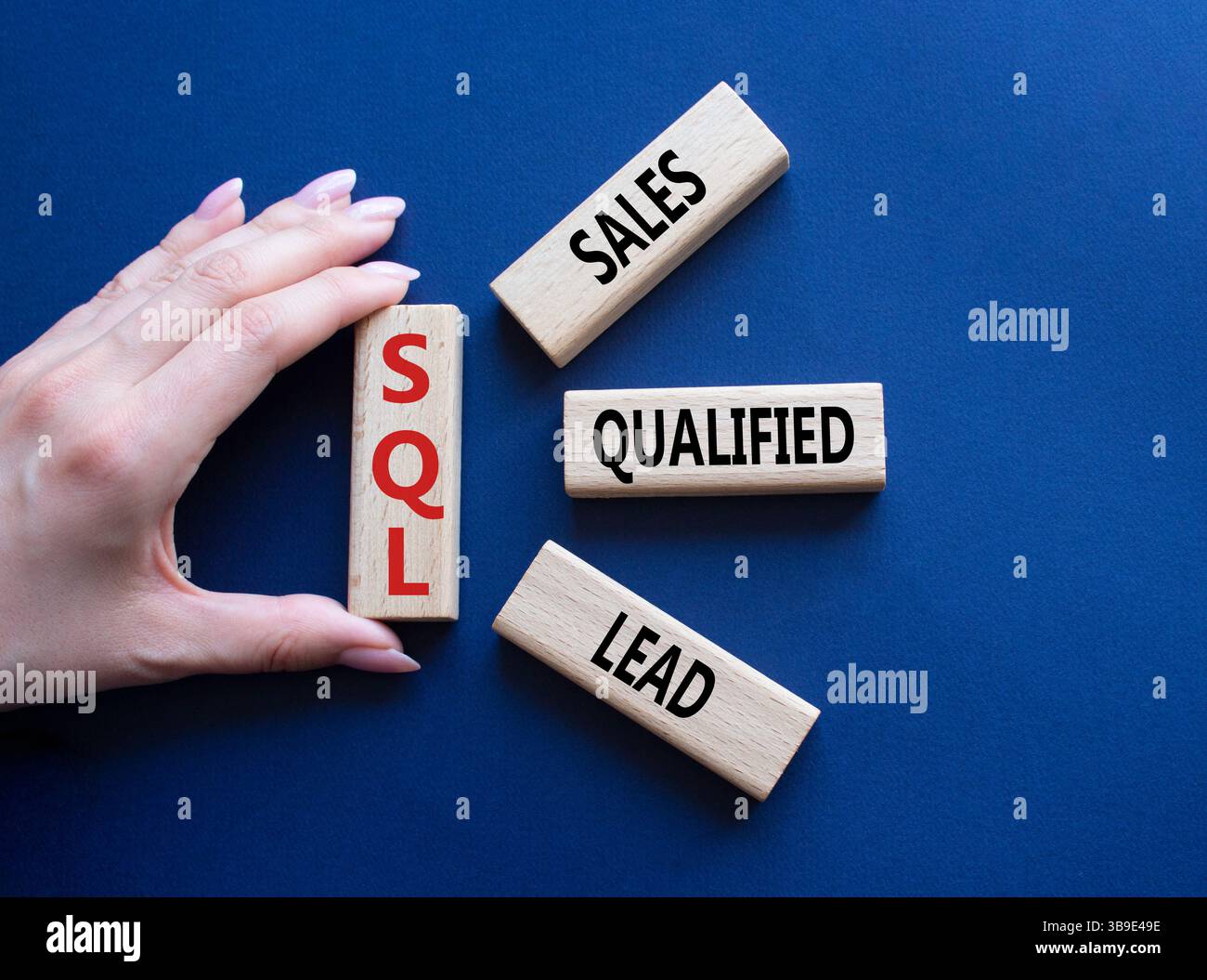 SQL - qualifizierter Lead für Vertrieb. Holzwürfel mit SQL-Wörtern. Geschäftsmann Hand. Wunderschöner tiefblauer Hintergrund. Business- und SQL-Konzept. Kopierbereich. Stockfoto
