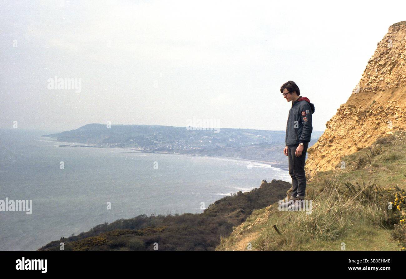 1971, historisch, ein junger Mann, Mitte Ende 20, unterwegs an der Küste, stehend über die Seite einer Klippe, England, Großbritannien. Stockfoto
