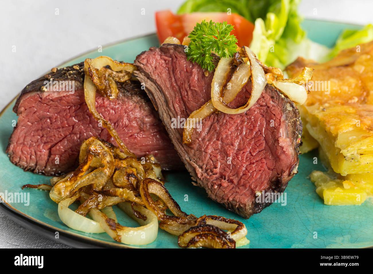 Nahaufnahme eines geschnittenen Steaks mit Zwiebeln Stockfoto