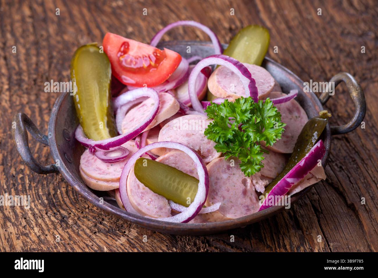 Bayerischer Wurstsalat auf dunklem Holz Stockfoto