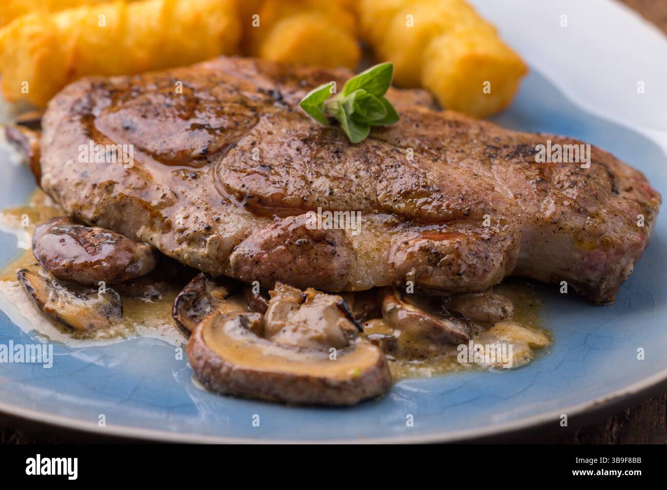 Nahaufnahme eines Schweinesteaks auf Pilzsauce Stockfoto