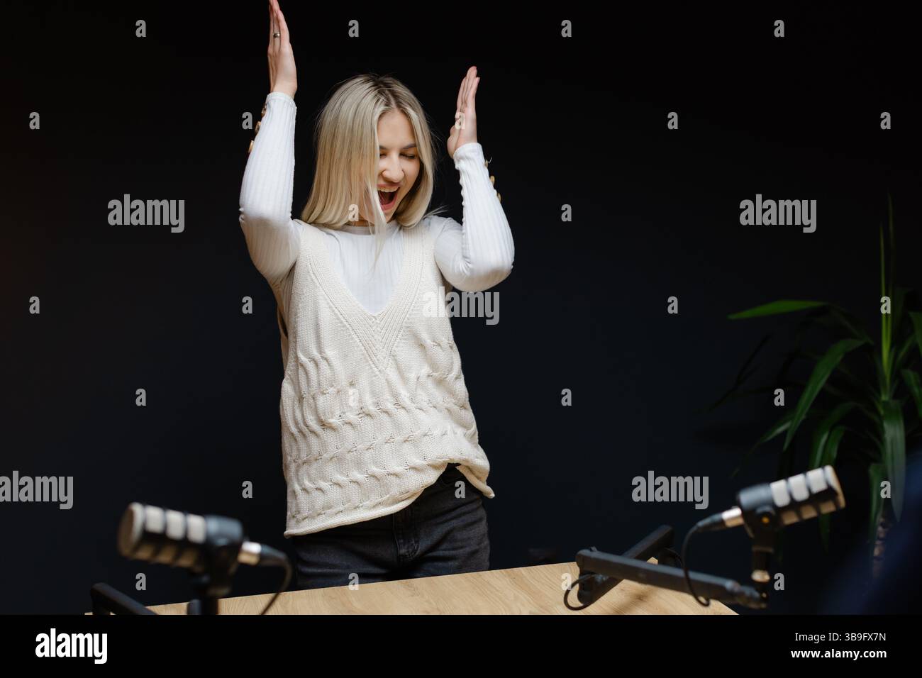 Weibliche Podcaster tanzen und lachen während einer Aufnahmesitzung in einem professionellen Studio und schaffen ansprechende Audioinhalte Stockfoto