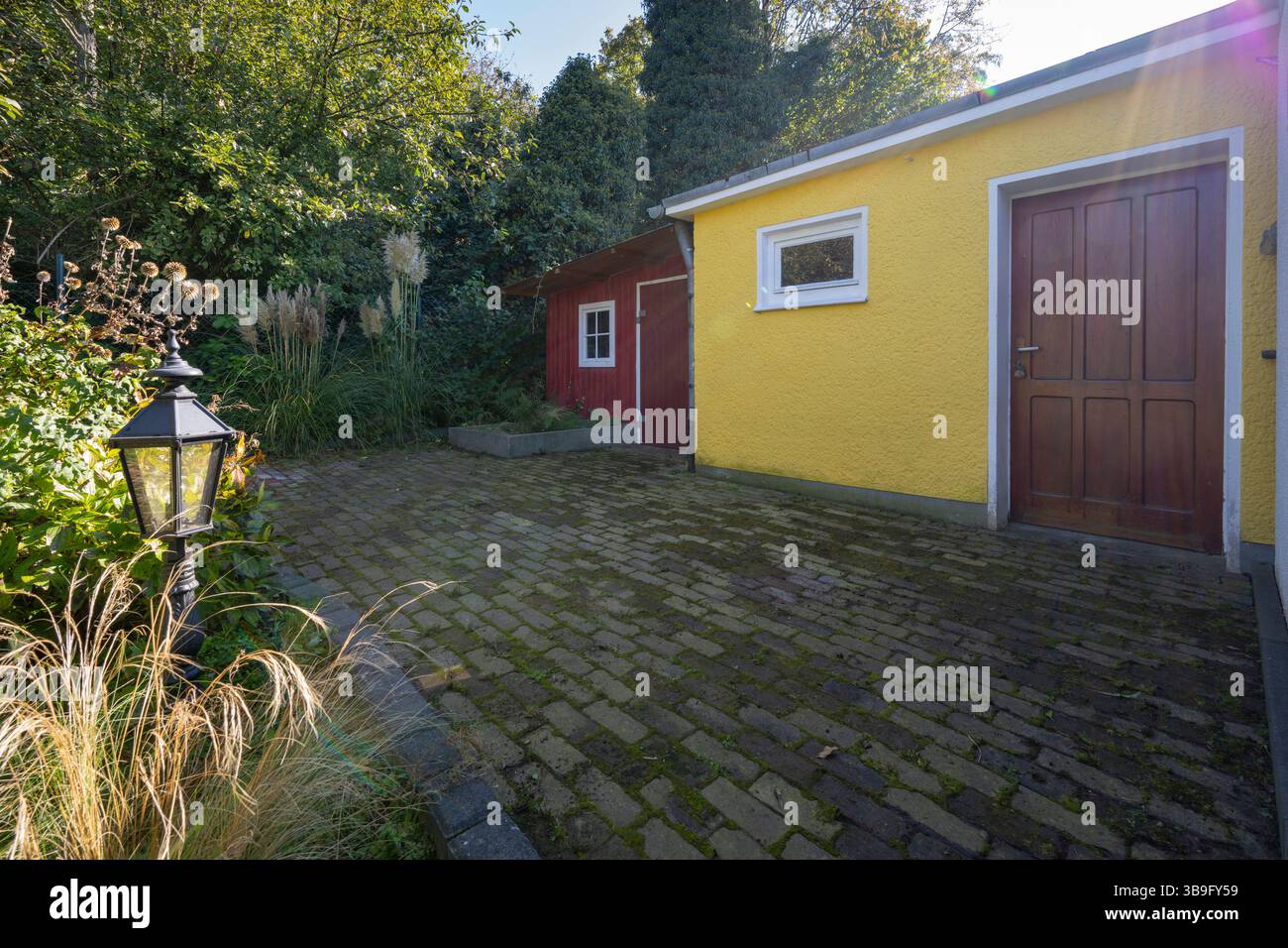 Deutschland, Nordrhein-Westfalen, Garten mit gepflastertem Platz und buntem Gartenhaus Stockfoto