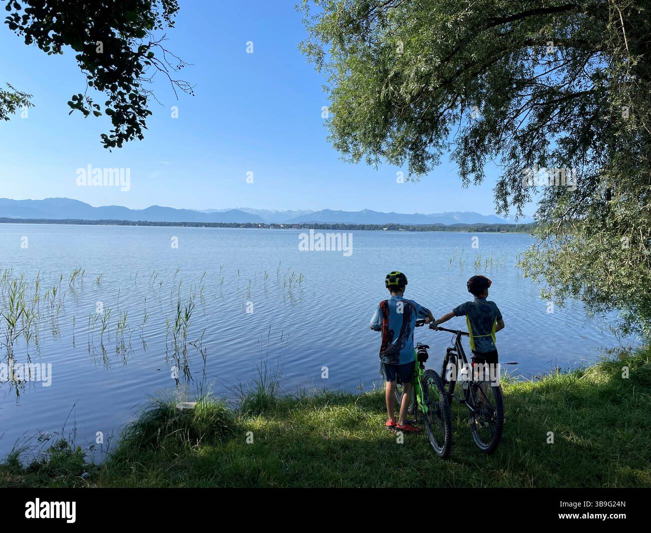 Zwei Kinder mit Fahrrädern am Ufer des Starnberger Sees, Alpenpanorama im Hintergrund, Natur, Aktivität, Sonne, Wasser, see, blauer Himmel, Wanderung, Bergtour, Fahrradtour, Bernried am Starnberger See, Oberbayern, Bayern, Deutschland Stockfoto