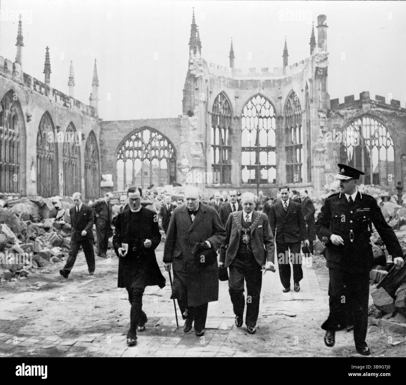 Premierminister Winston Churchill geht mit dem Bürgermeister von Coventry und einem Mitglied der Kirche von England durch das verfallene Schiff der Kathedrale von Coventry, nachdem sie im November 1940 von der deutschen Luftwaffe bombardiert wurde. Stockfoto