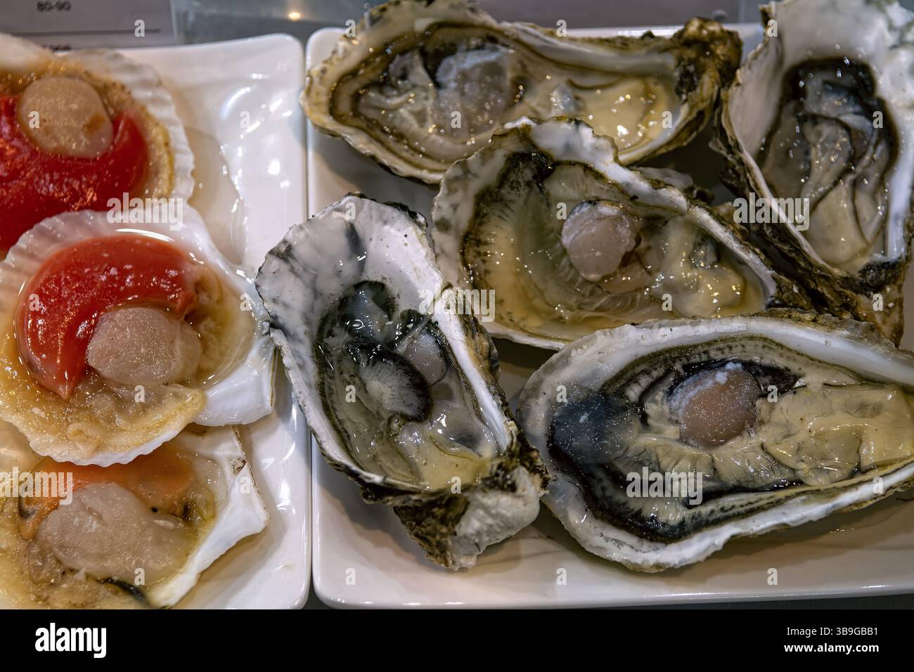 Frische Austern und Jakobsmuscheln in Muscheln im Meeresfrüchte-Restaurant, Blick von oben. Stockfoto