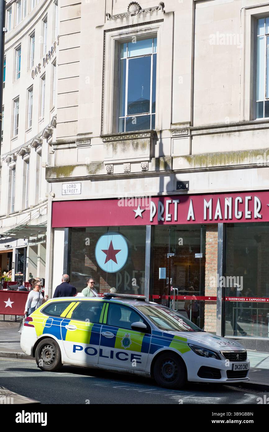 Ein Polizeiauto parkt auf einer Straße vor einer Pret A Manger. Menschen laufen in der Nähe. Das Gebäude ist aus hellem Stein in Liverpool, Großbritannien. Stockfoto