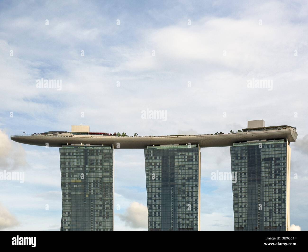 Das Marina Bay Sands Hotel in Singapur, das mit seinem einzigartigen bootförmigen Dachgarten auf drei hochragenden Wolkenkratzern vor einem klaren B besticht Stockfoto