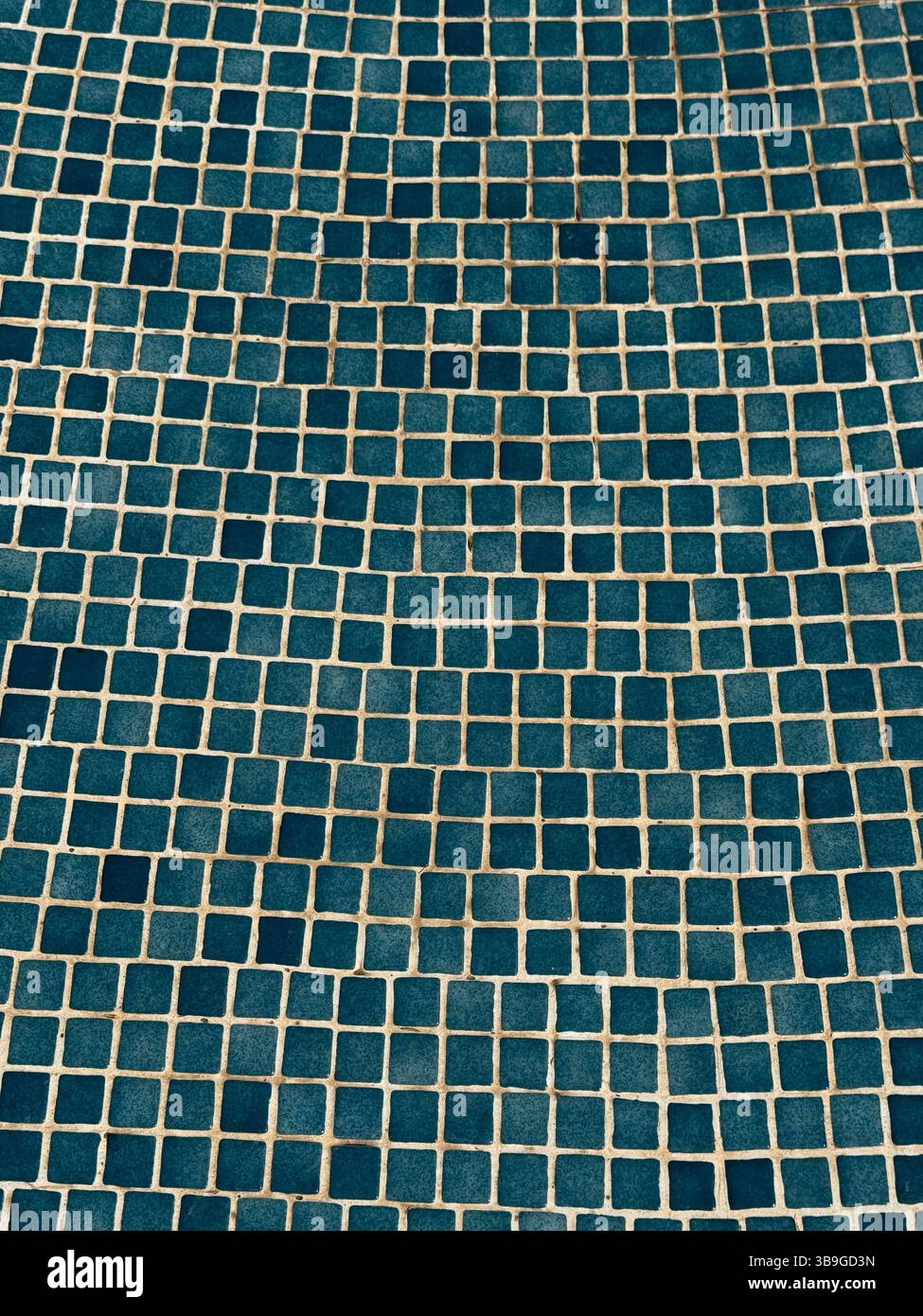 Ein visuell fesselndes abstraktes Bild einer blau gekachelten Wand mit geometrischem Mosaikmuster. Die sich wiederholenden Quadrate erzeugen eine ansprechende Textur und Stockfoto