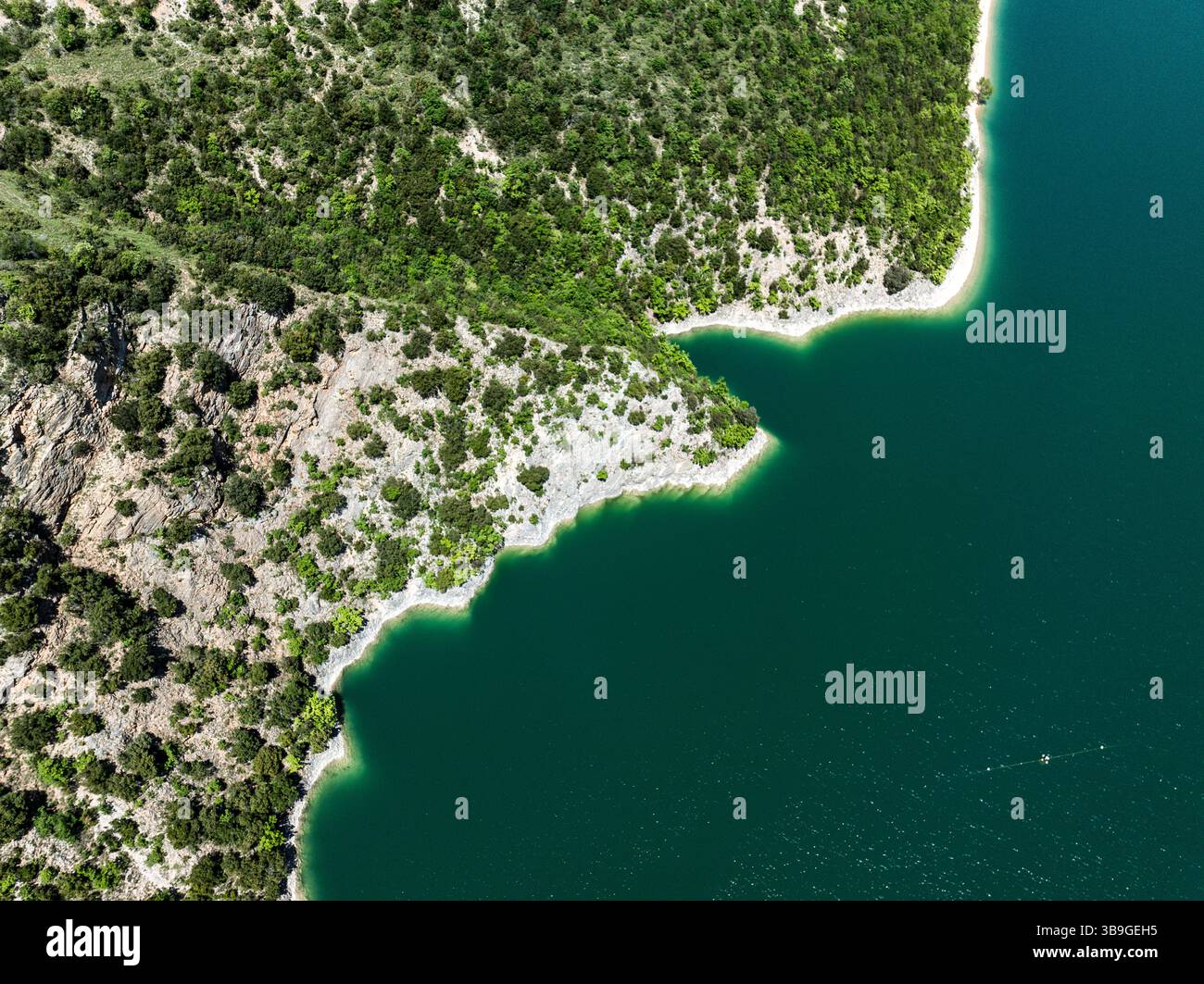 Luftaufnahme mit dem leuchtend grünen Laub und der felsigen Küste des Lago di Fiastra, Italien. Das kristallklare Wasser unterstreicht das atemberaubende natura Stockfoto