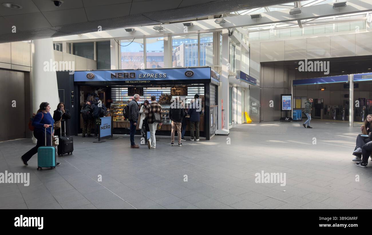 Indoor-Szene eines Caffe Nero Express-Stands innerhalb eines Verkehrsknotenpunktes. Mehrere Personen sind anwesend, mit einem gefliesten Boden und einem Hintergrund aus Fenstern und Trans Stockfoto Indoor-Szene eines Caffe Nero Express-Stands innerhalb eines Verkehrsknotenpunktes. Mehrere Personen sind anwesend, mit einem gefliesten Boden und einem Hintergrund aus Fenstern und Trans Stockfoto
