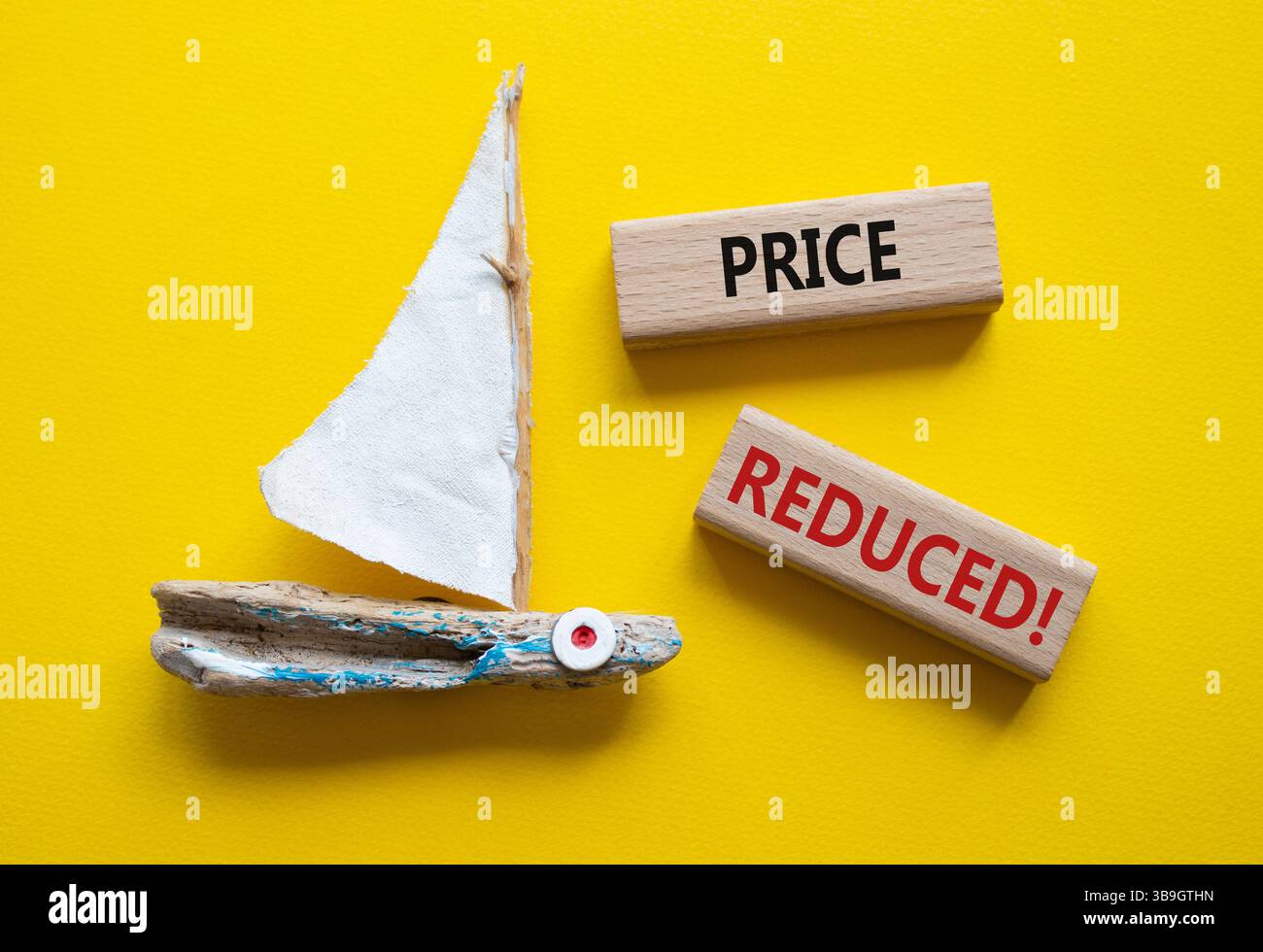 Symbol für reduzierte Preise. Konzeptwort Preisreduzierung bei Holzblöcken. Schöner gelber Hintergrund mit Boot. Business- und preisreduziertes Konzept. Spa kopieren Stockfoto