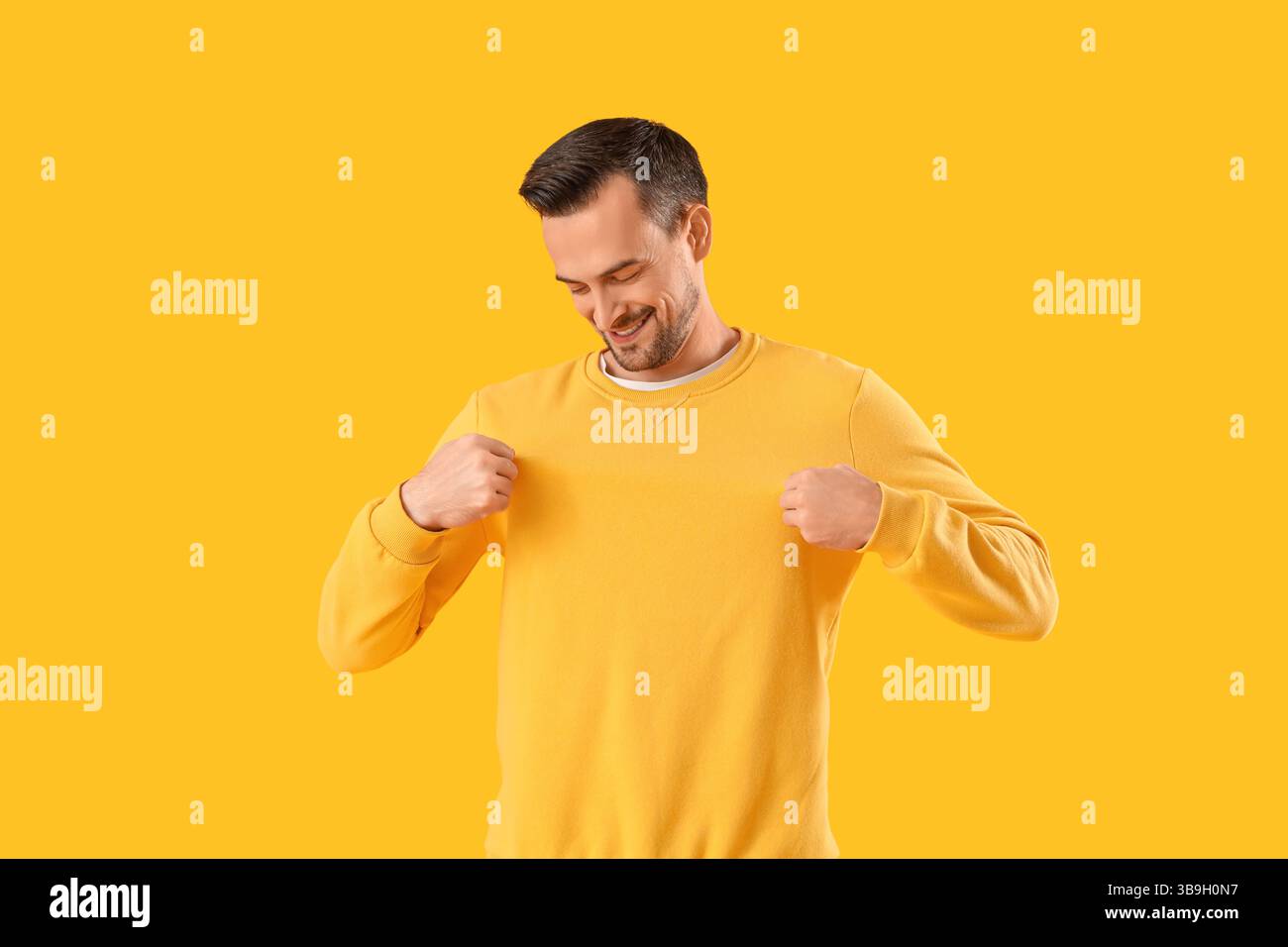 Junger Mann im Sweatshirt auf gelbem Hintergrund Stockfoto
