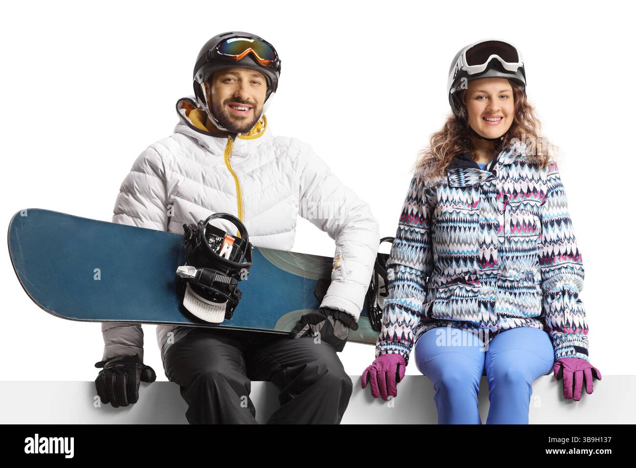 Junge Mann und Frau sitzen auf einer leeren Platte und halten ein Snowboard isoliert auf weißem Hintergrund Stockfoto