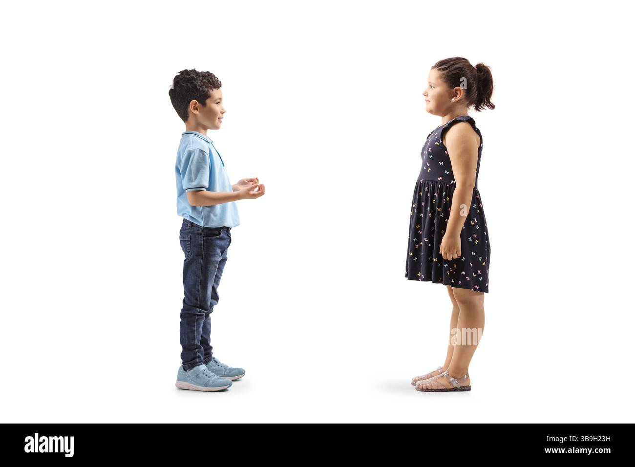 Profilaufnahme von zwei Kindern, die isoliert stehen und sprechen, auf weißem Hintergrund Stockfoto