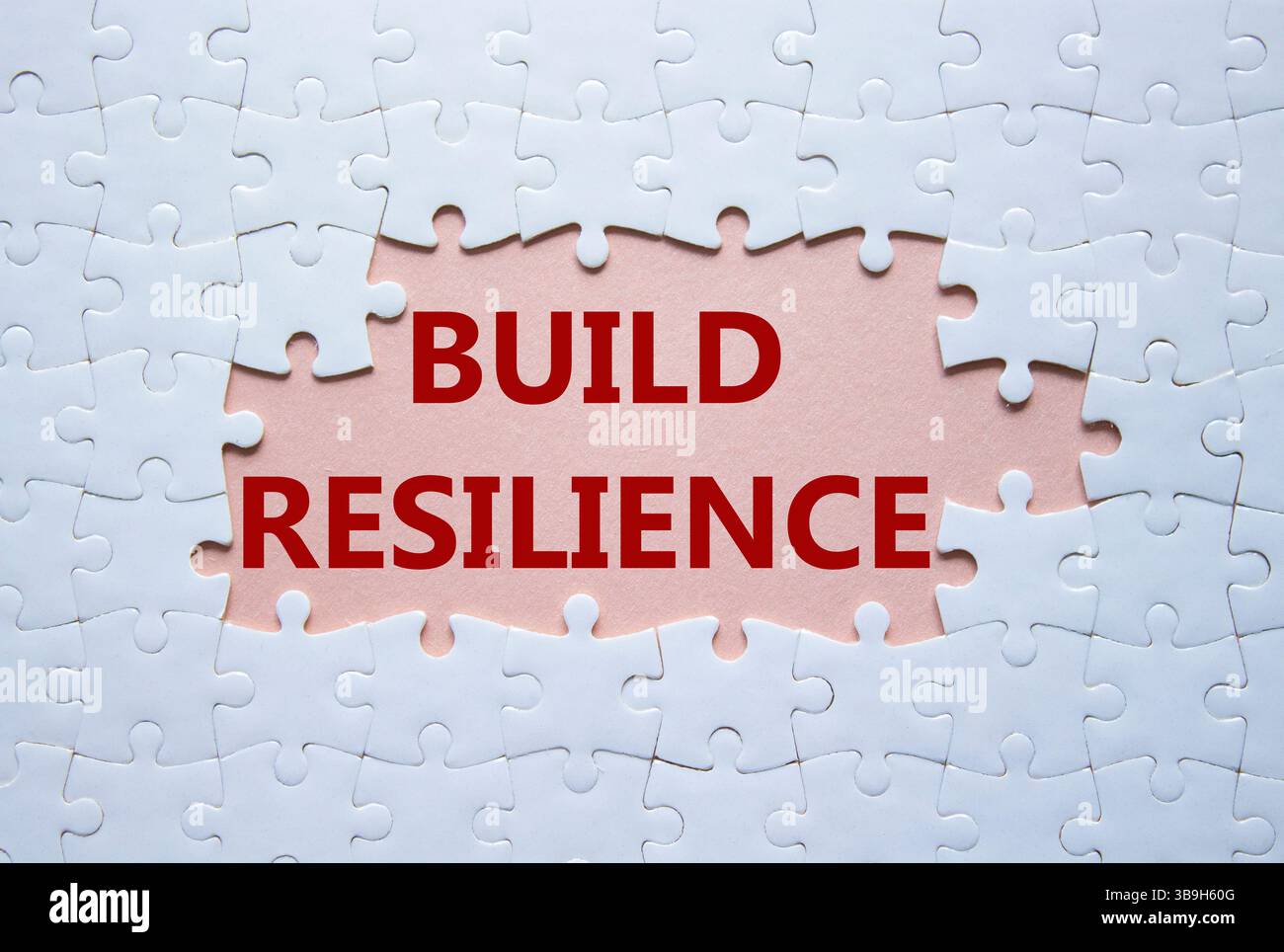 Symbol für Belastbarkeit erstellen. Weißes Puzzle mit Wörtern schafft Widerstandsfähigkeit. Schöner rosafarbener Hintergrund. Business- und Build Resilience-Konzept. Kopierbereich. Stockfoto