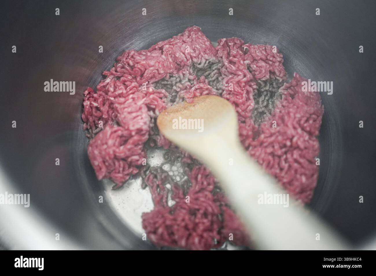 Eine Pfanne Hackfleisch wird mit einem Holzlöffel gekocht Stockfoto