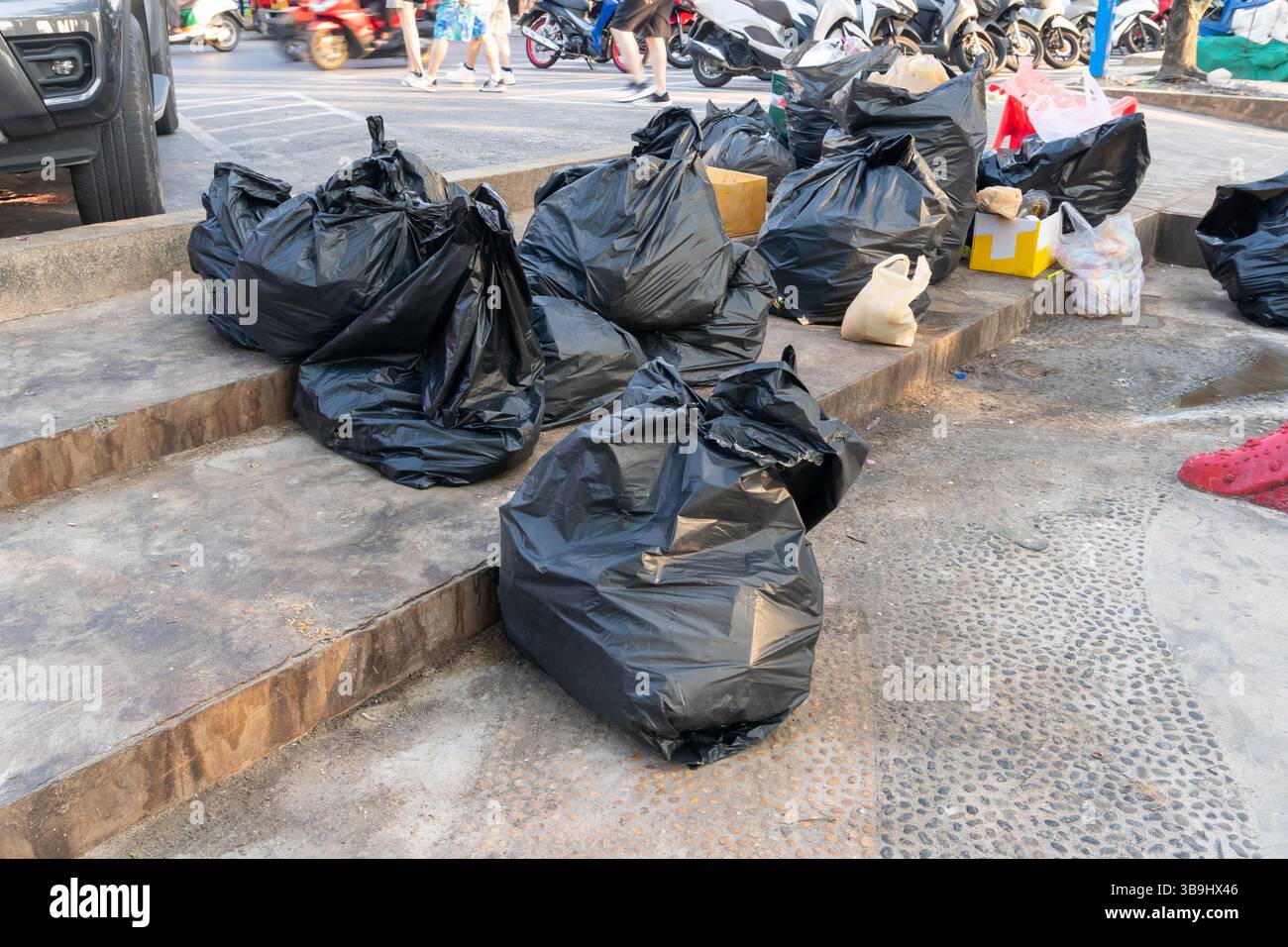 Eine große Gruppe von Abfall oder Müll in schwarzen Plastiktüten auf der Mülldeponie befindet sich auf dem Fußweg in der Innenstadt. Stockfoto