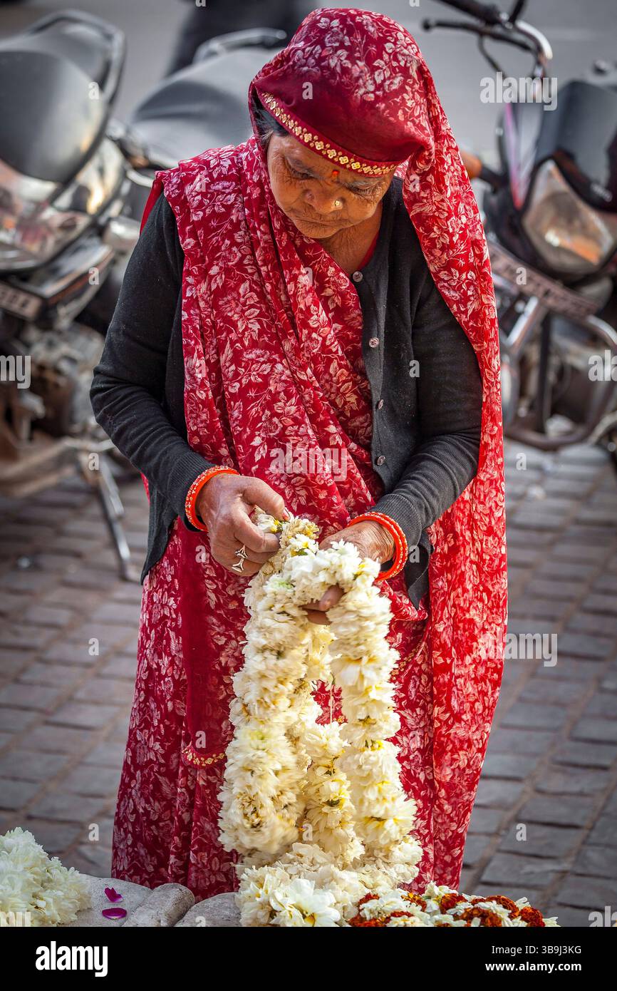 Einheimische indische Frau, die eine traditionelle Girlande aus weißen Jasminblüten (Gajra) zubereitet, Jaipur, Indien Stockfoto