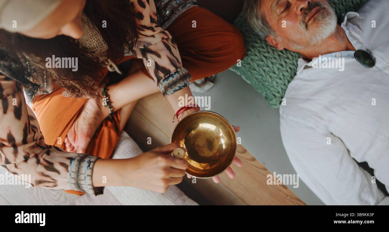 Tibetische Schüssel, Entspannung und Hände einer Person im Studio für Wellness Retreat, Heilung und Meditation. Chakra-Balance, Ruhe- und Klangtherapie mit oben Stockfoto