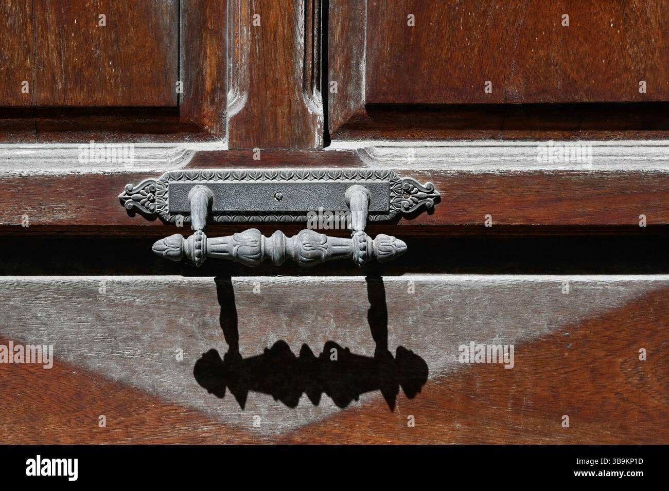 Nahaufnahme des alten Metalltürgriffs an alter Holztür mit Schatten Stockfoto