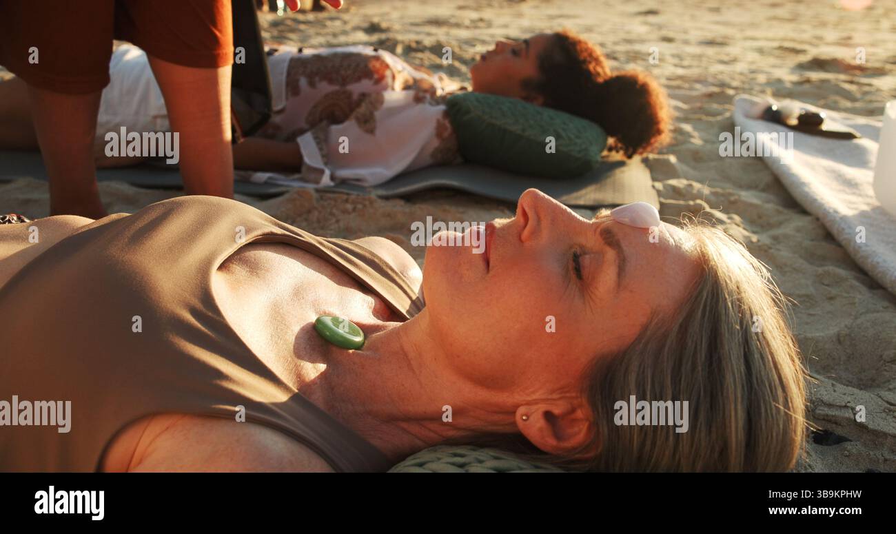 Frau, Kristall und Boden am Strand mit Chakra Gleichgewicht, Therapie und Outdoor für Heilung im Urlaub. Menschen, Stein und ganzheitlich mit Mineralien Stockfoto