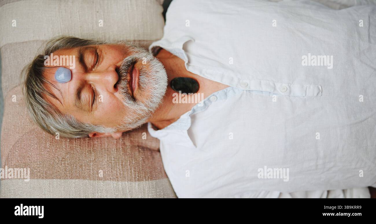 Kristall, Meditation und Frieden mit asiatischem Mann auf dem Boden für Energiehaushalt, Heilritual oder Spiritualität. Chakra, Zen oder ganzheitlich mit über dem Senior Stockfoto