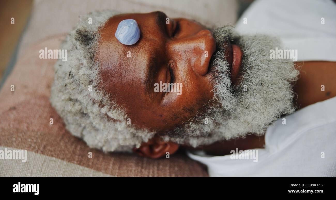 Kristall, Zen und ganzheitlich mit schwarzem Mann auf dem Boden für Energiehaushalt, Meditation oder Spiritualität. Chakra des dritten Auges, Frieden oder Heilung mit Senior Stockfoto