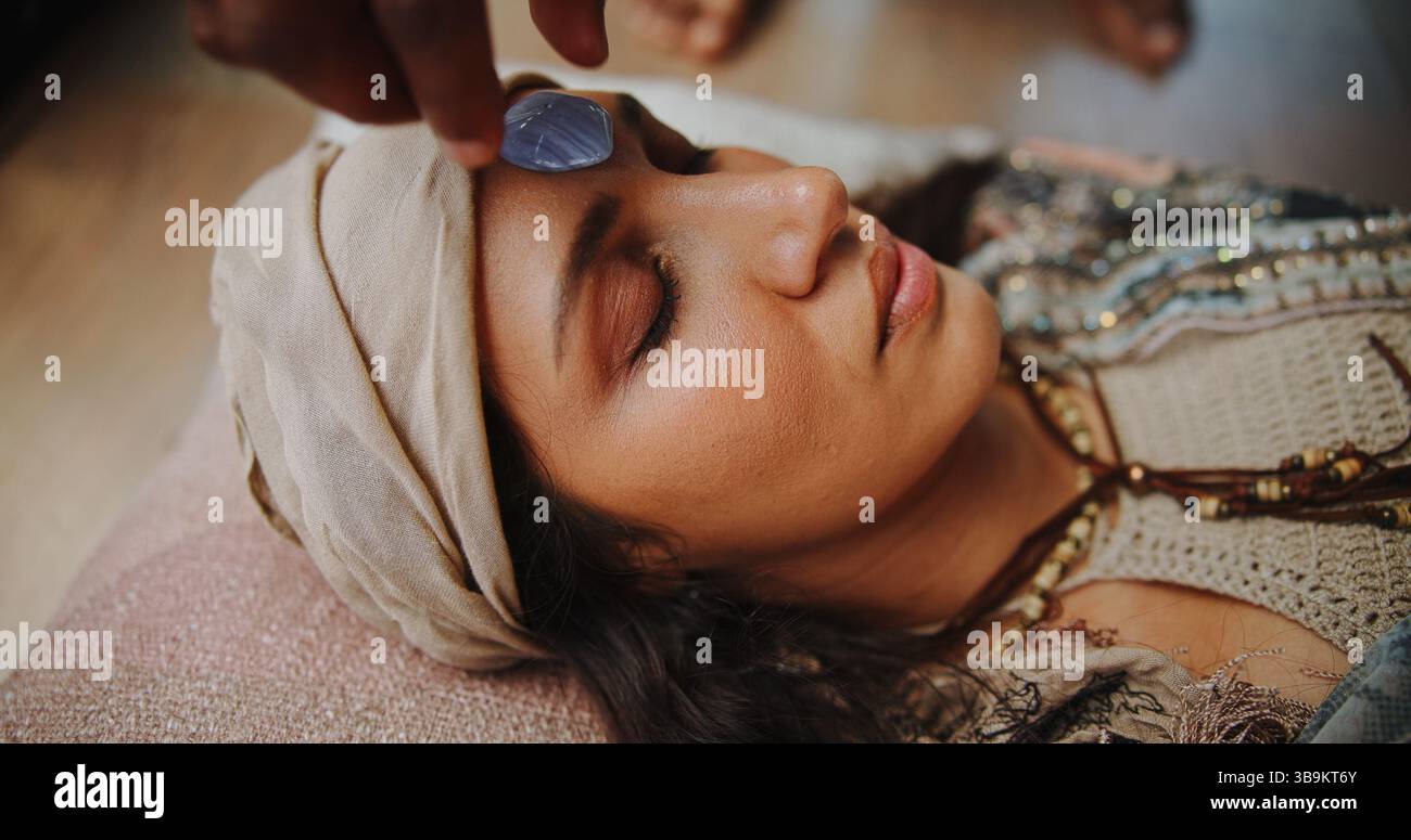 Frau, Kristall und Stirn mit Händen für Chakra auf dem Boden, Energie und Therapie mit Erholung im Urlaub. Menschen, Felsen und ganzheitliche Pflege mit Mineralien Stockfoto