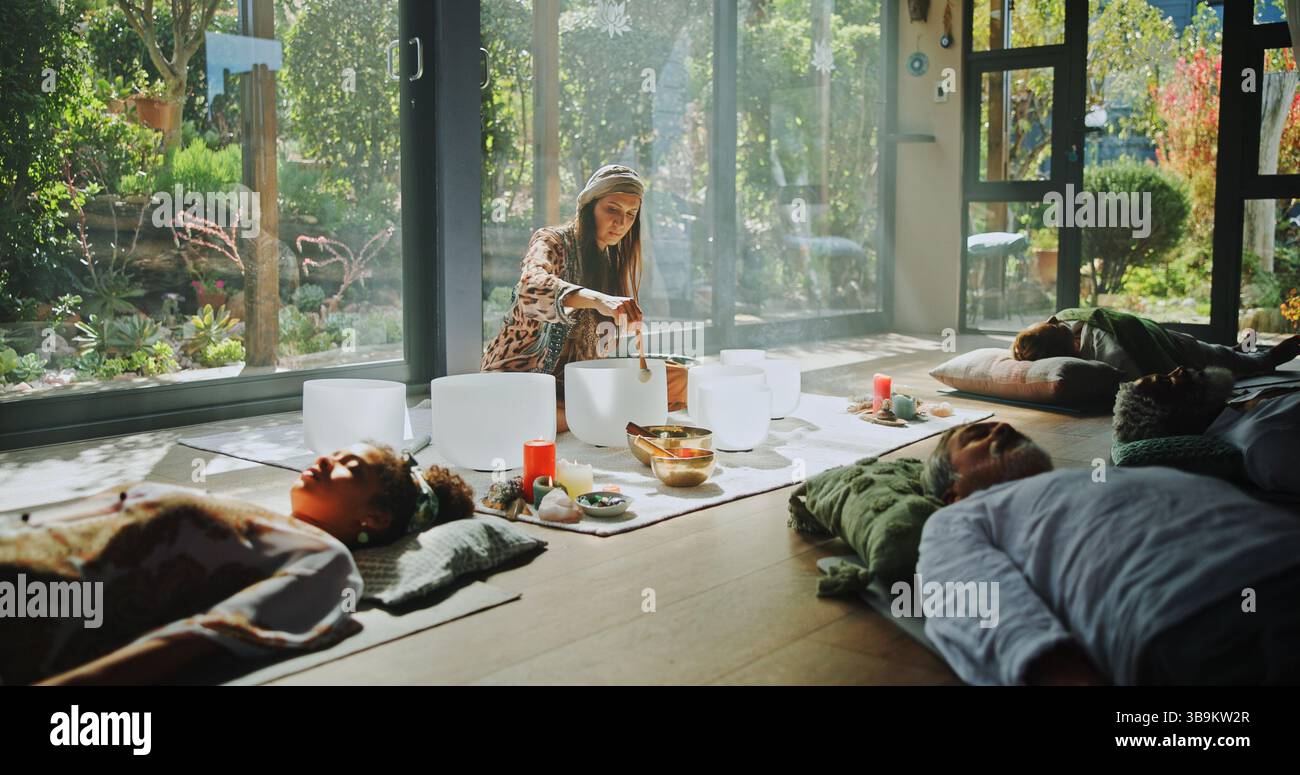 Frau, singende Schüssel und Heilung auf dem Boden für Therapie, Frequenz und Frieden mit Achtsamkeit im Studio. Gruppe, Schamane und ganzheitlich mit Reiseleiter in der Klasse Stockfoto