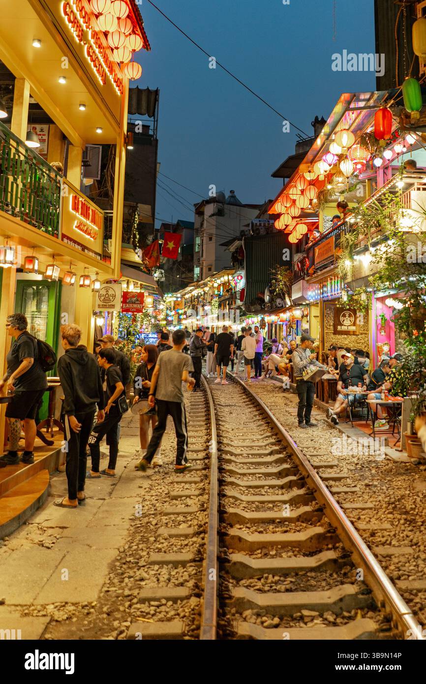 Eine lebhafte Abendszene entfaltet sich entlang der Bahnstraße von Hanoi, voller Menschen und lebhafter Atmosphäre. Die Straße ist mit dekorativen Laternen beleuchtet. Stockfoto
