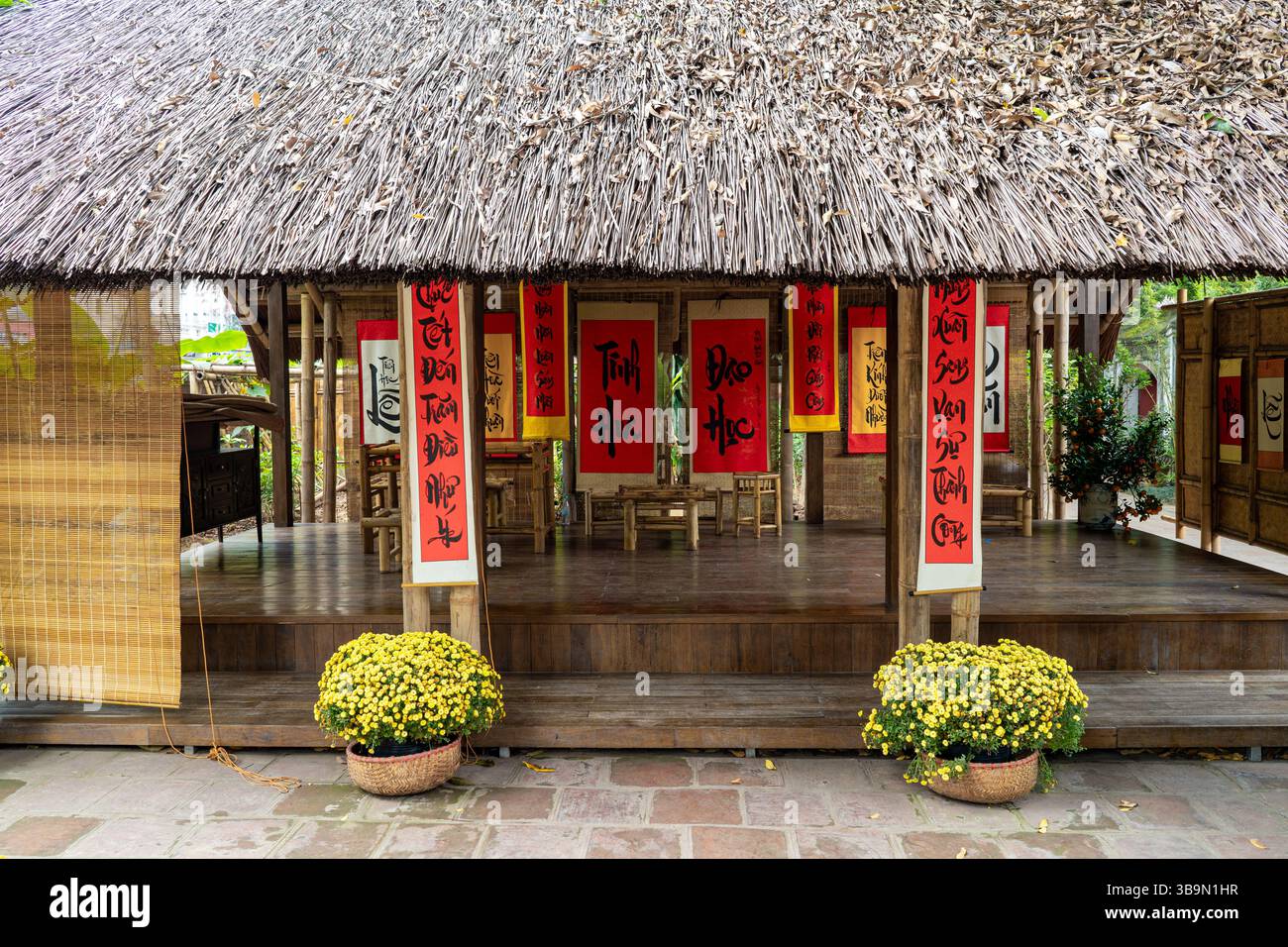 Eine bezaubernde Szene entfaltet sich in einem traditionellen vietnamesischen Gebäude, das mit Kalligrafie und lebhaften Dekorationen geschmückt ist. Die Holzarchitektur trägt dazu bei Stockfoto