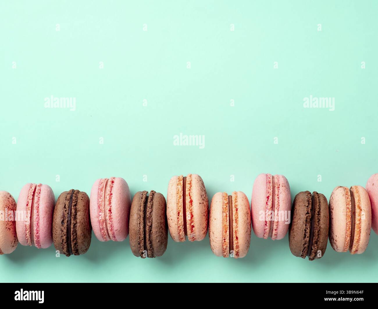 Makronen mit Kopierbereich. Reihe perfekter französischer Makronen oder Makronen auf blauem türkisfarbenem Hintergrund. Draufsicht oder flache Lage Stockfoto