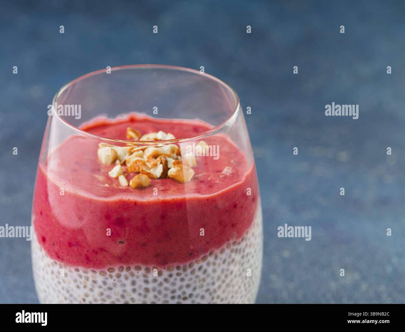 Nahaufnahme von Chia Pudding mit roten Beeren pürieren und gehackten Mandeln. Kopieren Sie Platz für Text Stockfoto