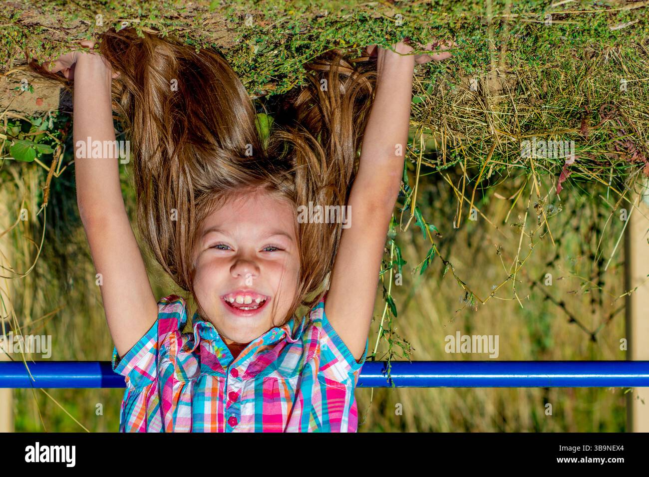 Porträt eines lächelnden kaukasischen Kindes von 7 bis 8 Jahren mit Kopf über Fersen Stockfoto