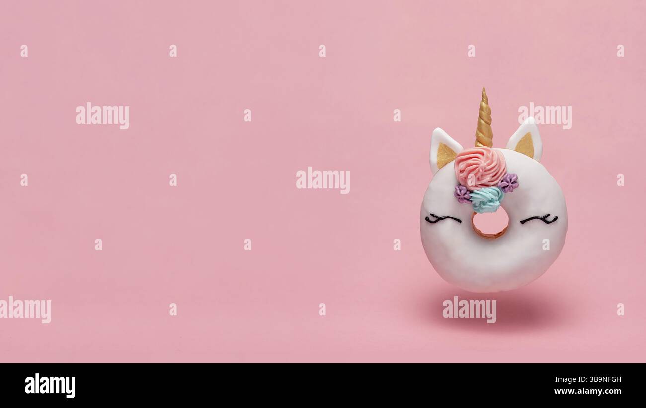 Einhorn Donut schweben in der Luft über rosa Hintergrund. Trendiges Donut-Einhorn mit weißer Glasur. Kopierbereich für Text Stockfoto