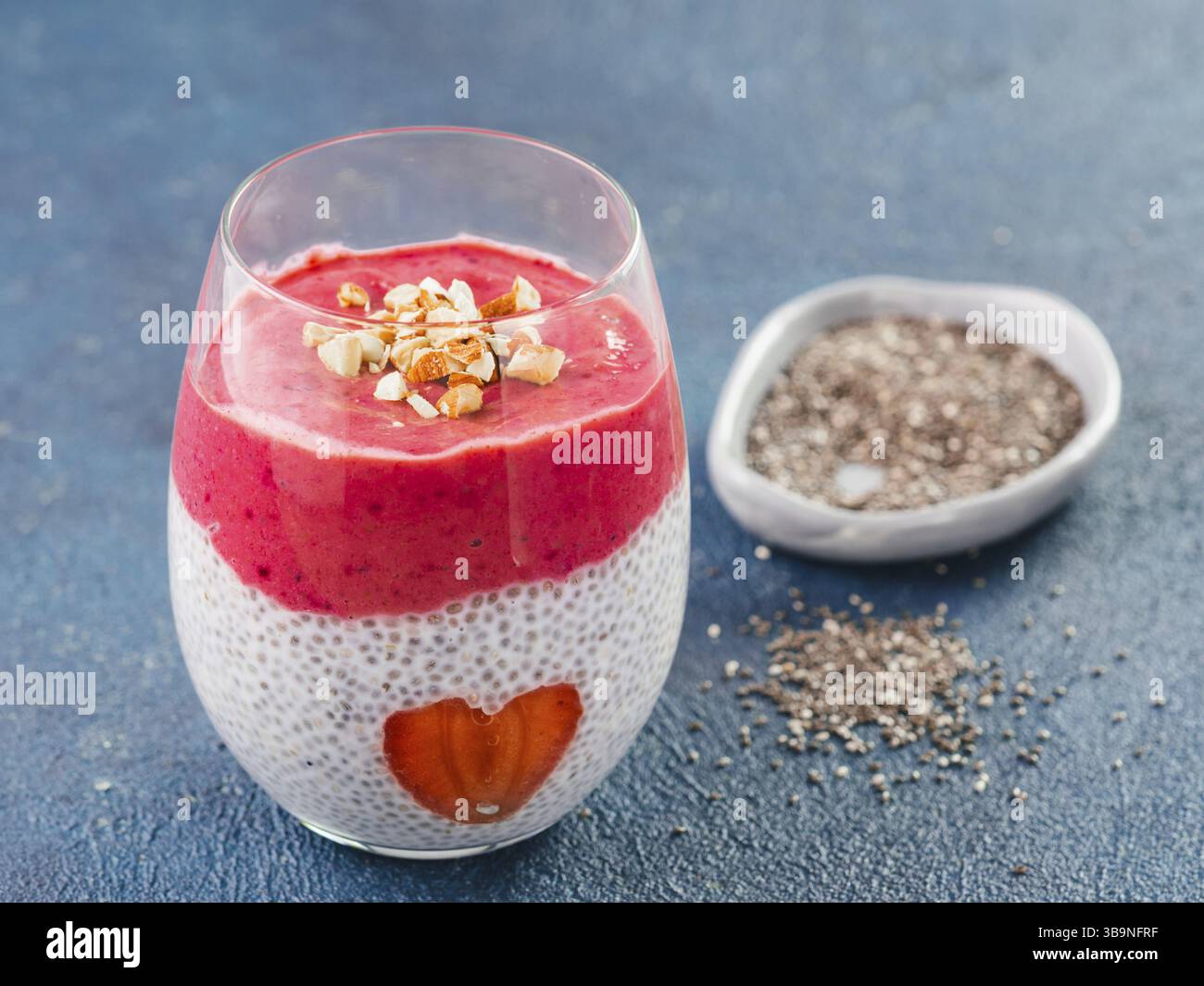Idee für gesundes Frühstück am Valentinstag: Chia Pudding mit roten Beeren Püree, gehackte Mandeln auf und Erdbeere in der Form des Herzens. Kopieren Sie sp Stockfoto