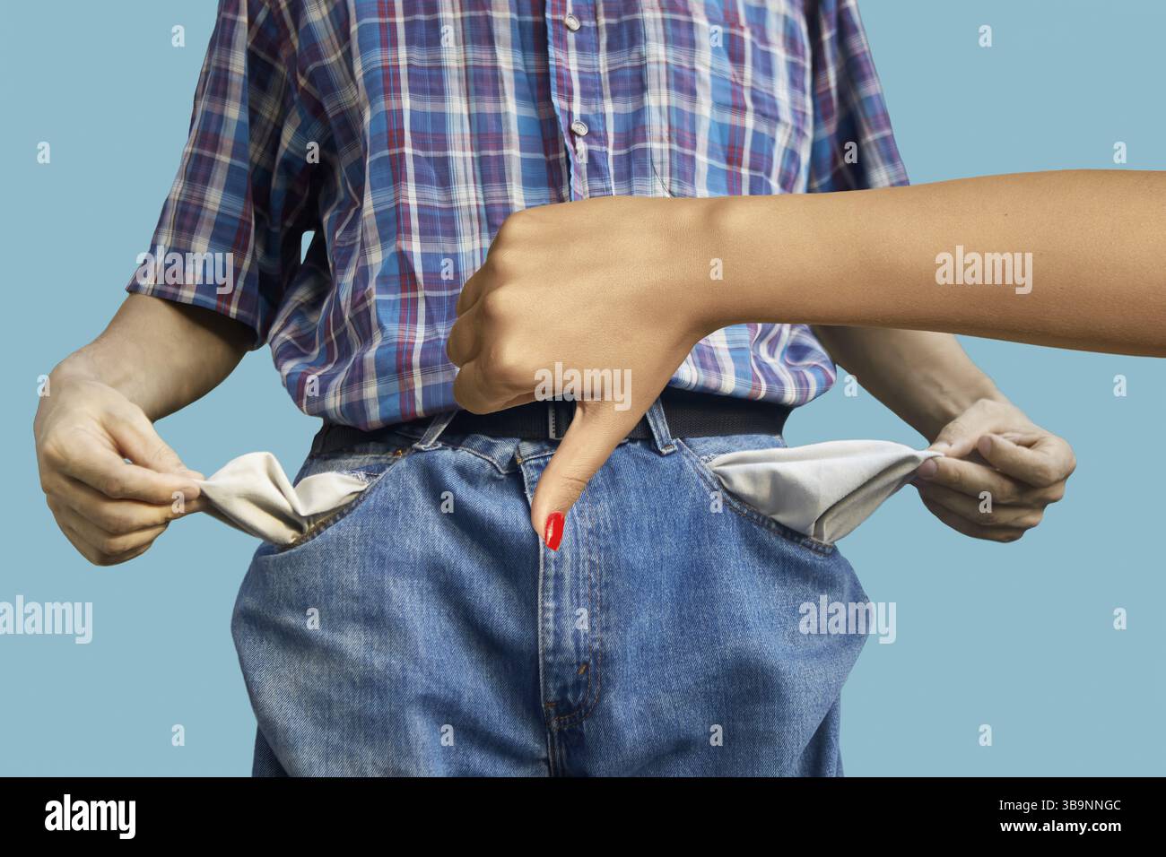 Weibliche Hand mit Leugnungsgeste - Daumen nach unten. Im Hintergrund ist ein verschwommenes Bild eines Bettlers, der seine leeren Taschen zeigt. No-Geld-Konzept. Wom Stockfoto