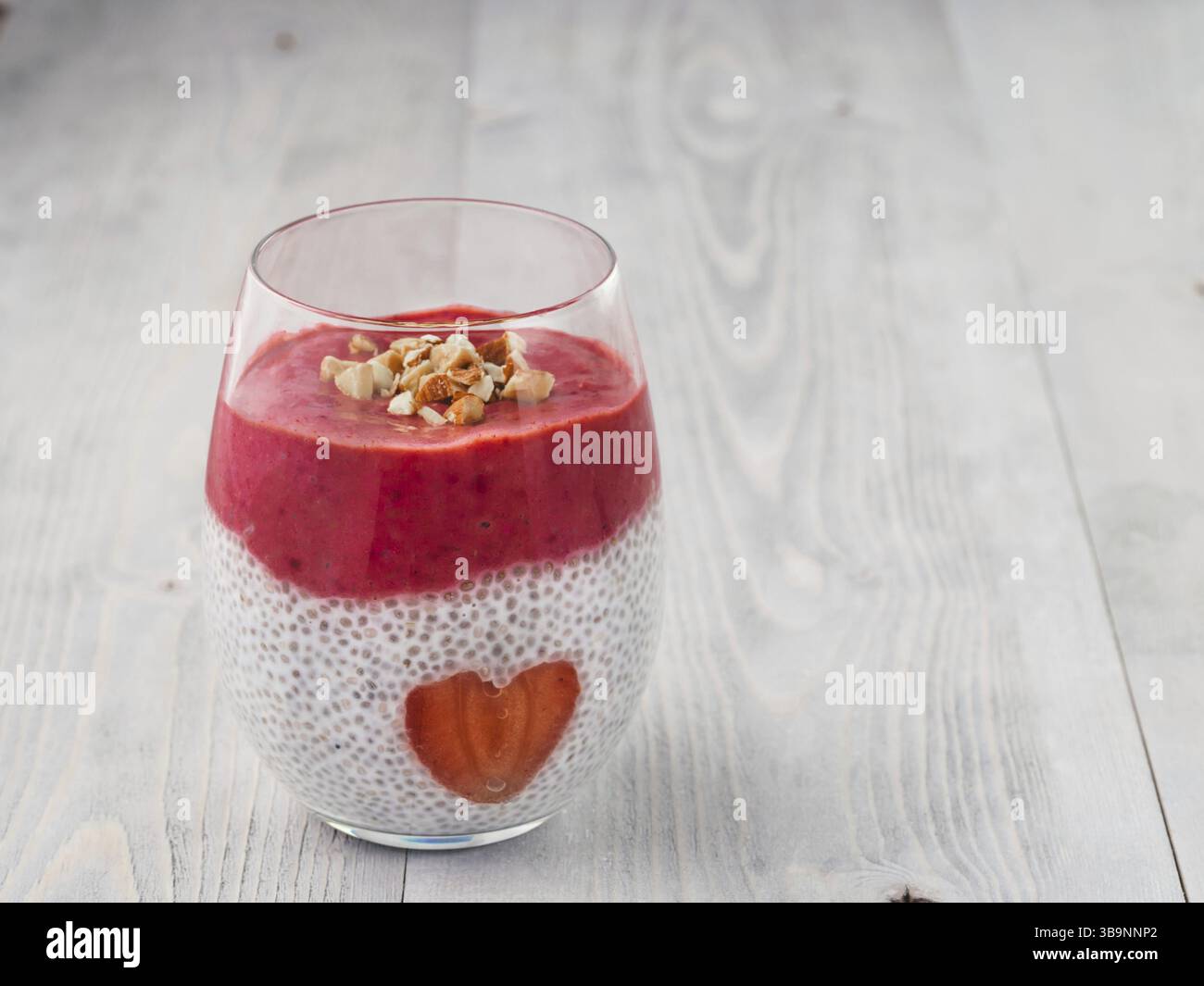 Idee für gesundes Frühstück am Valentinstag: Chia Pudding mit roten Beeren Püree, gehackte Mandeln auf und Erdbeere in der Form des Herzens. Kopieren Sie sp Stockfoto