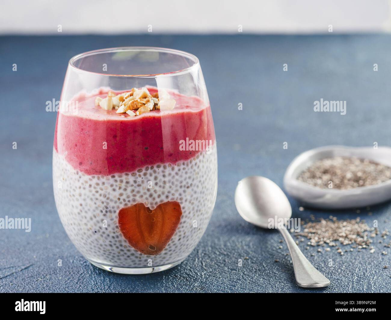 Idee für gesundes Frühstück am Valentinstag: Chia Pudding mit roten Beeren Püree, gehackte Mandeln auf und Erdbeere in der Form des Herzens. Kopieren Sie sp Stockfoto