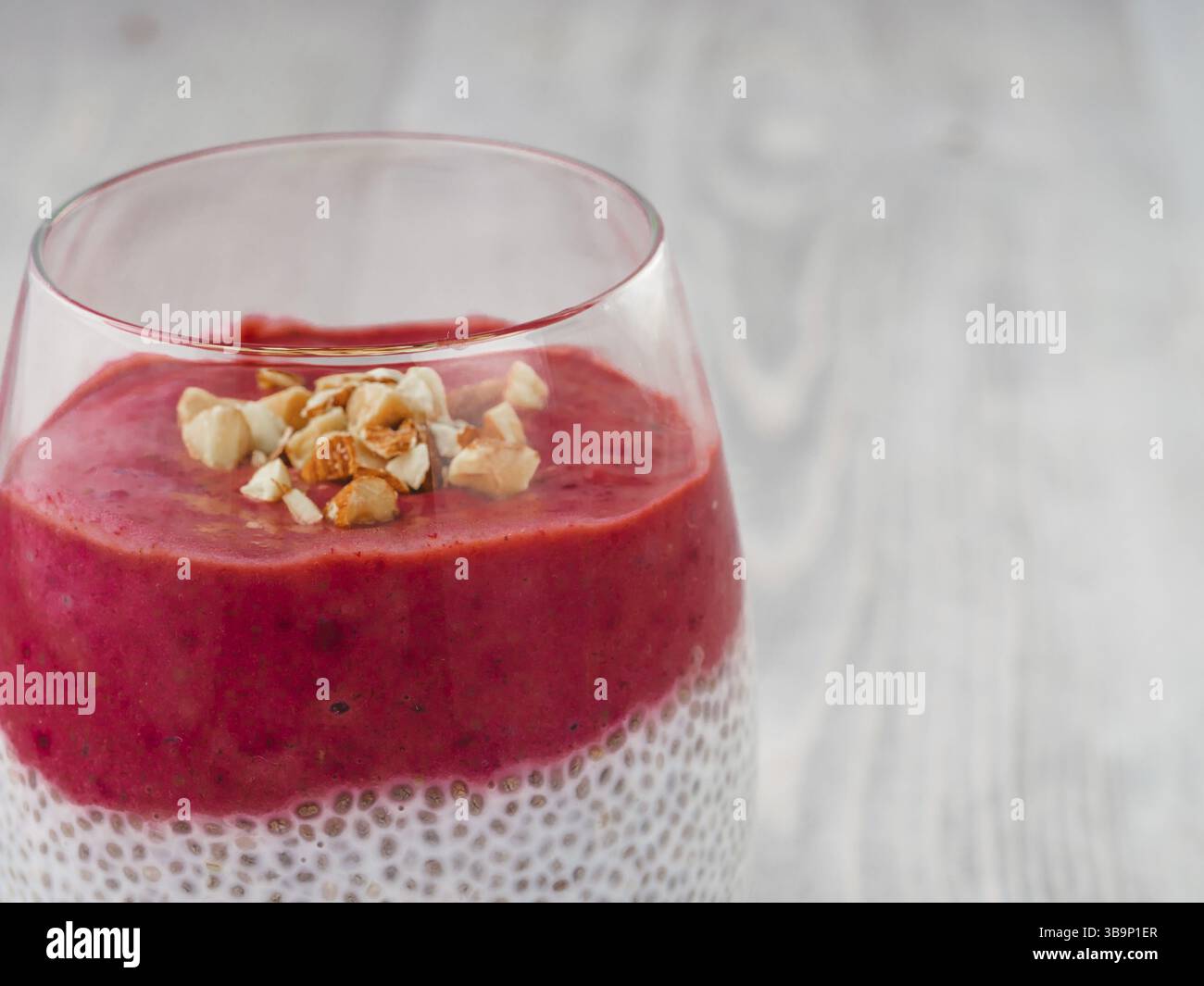 Nahaufnahme von Chia Pudding mit roten Beeren pürieren und gehackten Mandeln. Kopieren Sie Platz für Text Stockfoto