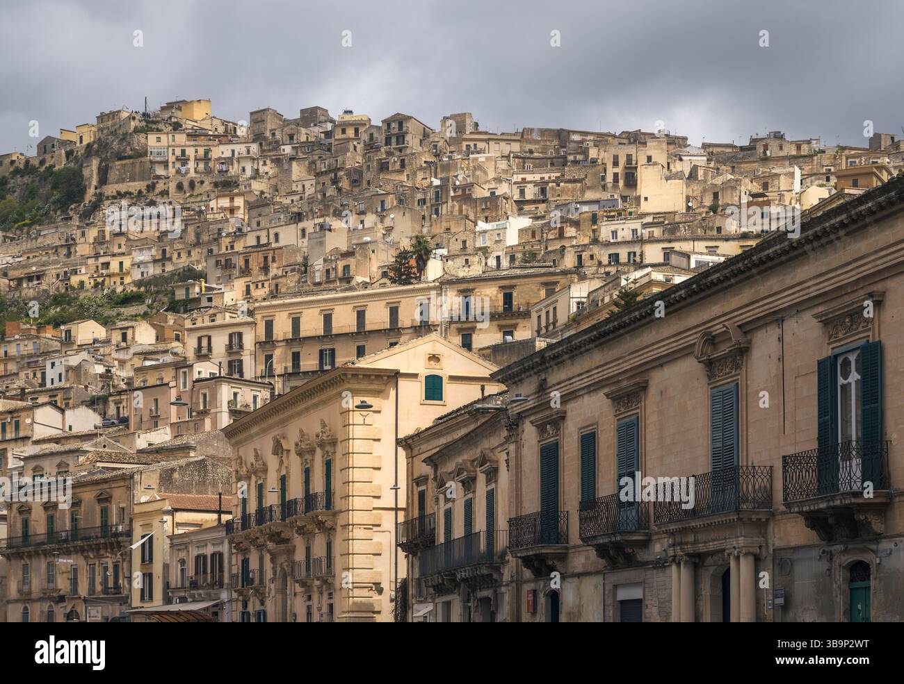 Atemberaubende Gebäude in Modica zeigen elegante Architektur vor den bewölkten sizilianischen Hügeln, Italien Stockfoto