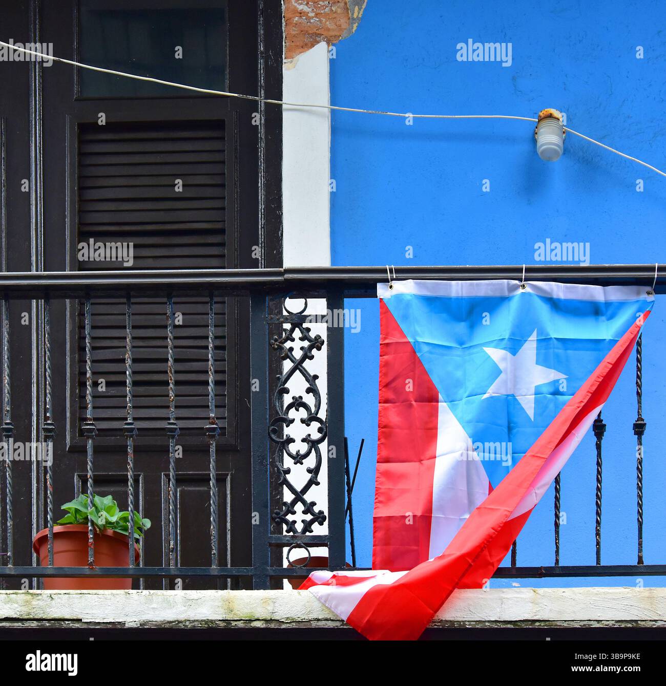 Puerto-ricanische Flagge fliegt von einem beschädigten Balkon im zweiten Stock in Old San Juan, nachdem Hurrikan Maria (2017) die Insel verwüstet hatte. Ein Netzkabel führt über Stockfoto