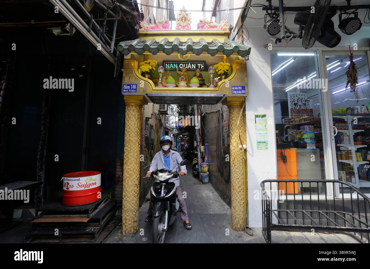 Ho Chi Minh, Vietnam - 26. Dezember 2022: Ein Motorradfahrer fährt mit seinem Fahrrad durch den Eingang einer engen Gasse in der Nähe der Bui Vien Straße in Saigon. Stockfoto