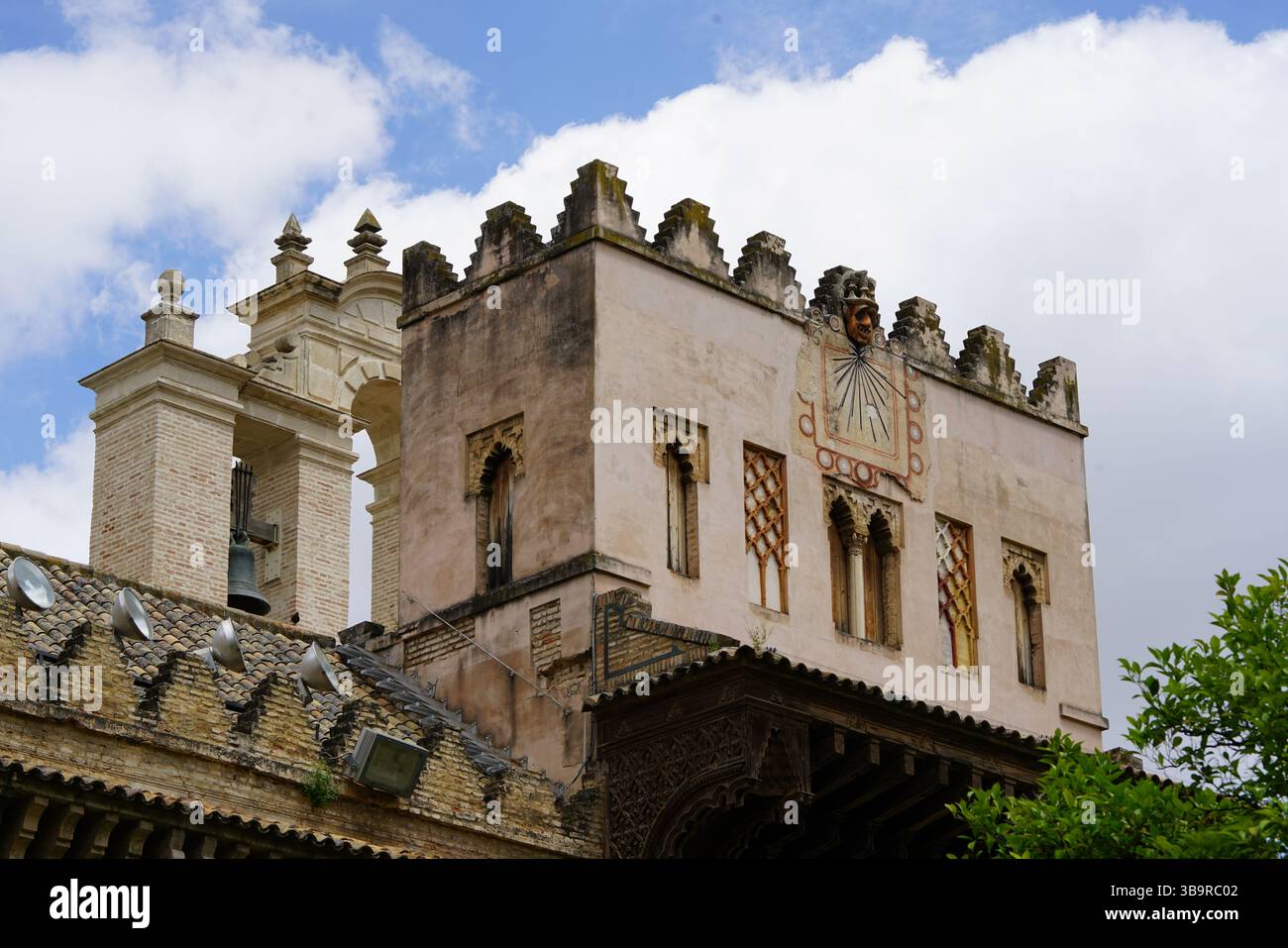 Historischer Palastturm mit Zinnen und dekorativen Fassadendetails im Royal Alcázar in Sevilla, Spanien, fotografiert unter blauem Himmel. Sevilla Stockfoto