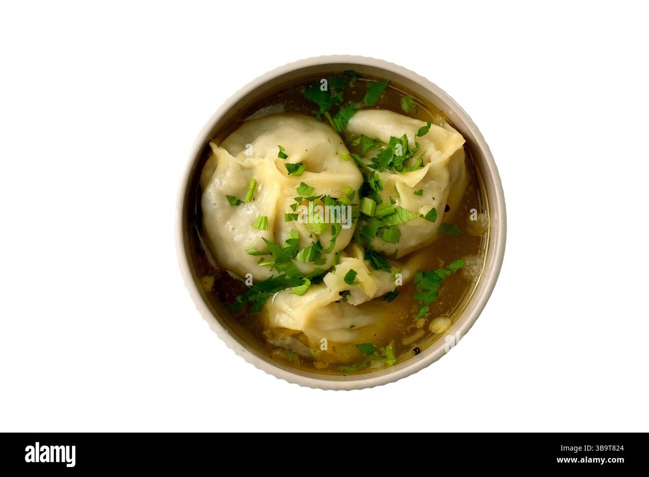 Manti (Manti oder Manty) in dicker Fleischsoße mit Kräutern in einer weißen Schüssel. Ein zentralasiatisches Gericht. Stockfoto