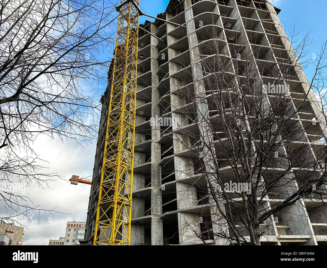 Mehrstöckiger Wohnkomplex im Bau mit gelbem Kran. Betonabschnitte. Bild für Wohnraumplanung und Immobilieninhalte Stockfoto