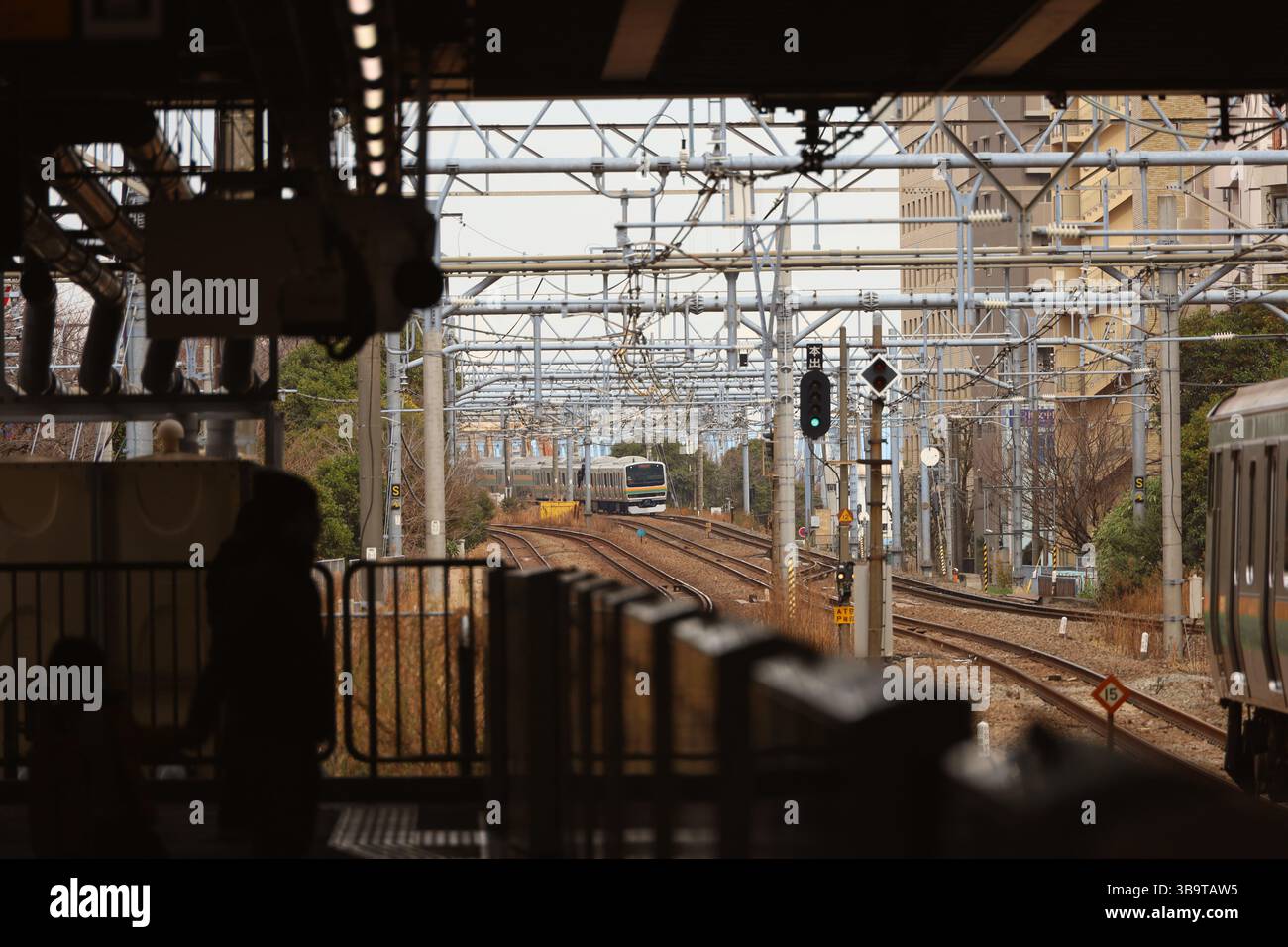 Alltagsszenen in Japan Eine Szene, in der Eltern und Kinder auf einen Zug auf einem Bahnsteig warten und Züge durch die Stadt fahren Stockfoto