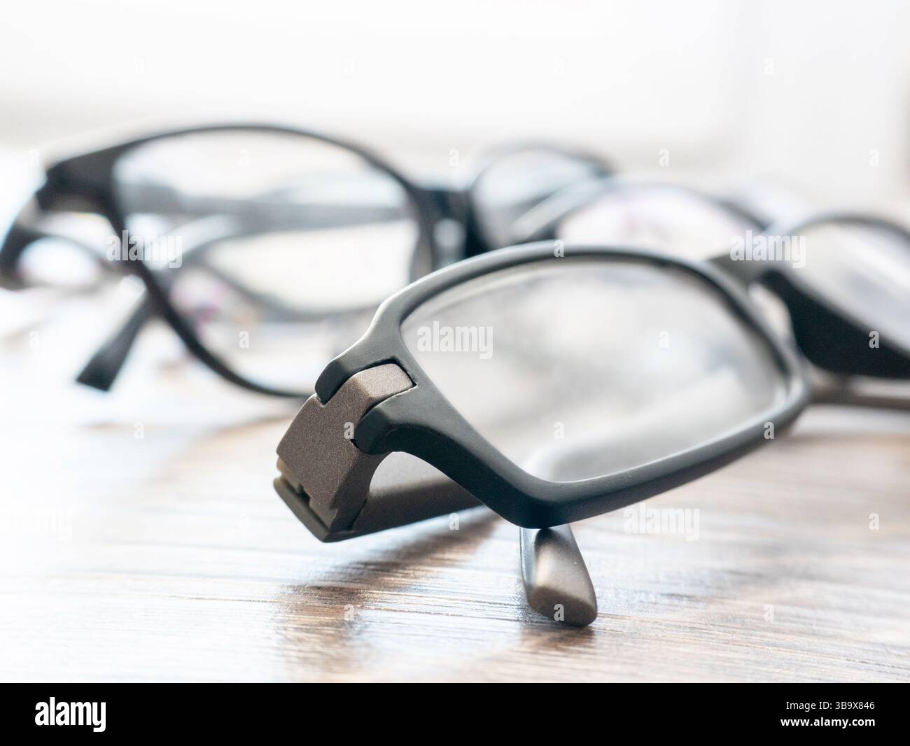 Auf einem Holztisch werden verschiedene Brillen ausgestellt. Das helle Tageslicht hebt die verschiedenen Stile und Rahmen hervor und sorgt so für einen einladenden geldautomaten Stockfoto